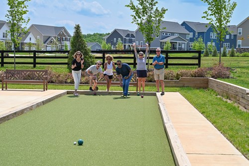 Residents playing lawn games on a community green with neighborhood homes in the background.
