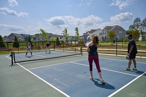 Active adults playing pickleball on outdoor courts in a suburban neighborhood